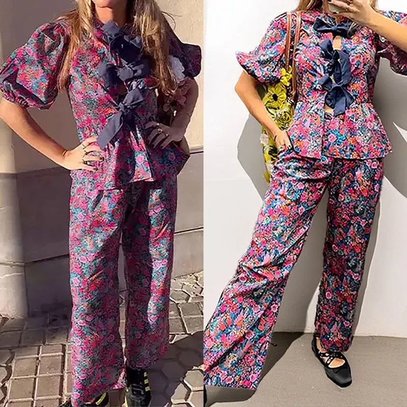 Women's floral print trousers suit with tie-neck puff sleeve top and matching trousers.