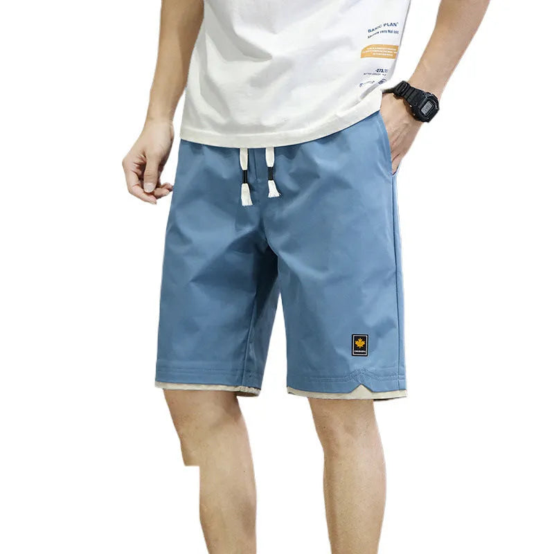 Man modelling loose-fitting straight-leg casual shorts in a solid colour on a beach.