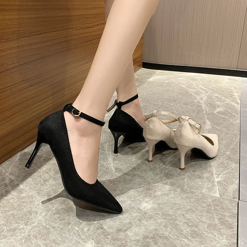 Women's black stiletto heel pump with ankle buckle detail and a rubber sole.