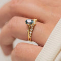 Gold plated women's ring with green zircon stone in floral design on a model's finger.