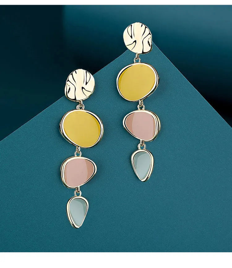 A pair of thin sterling silver stud earrings with Morandi-coloured wafer discs featuring an oil-drip texture.