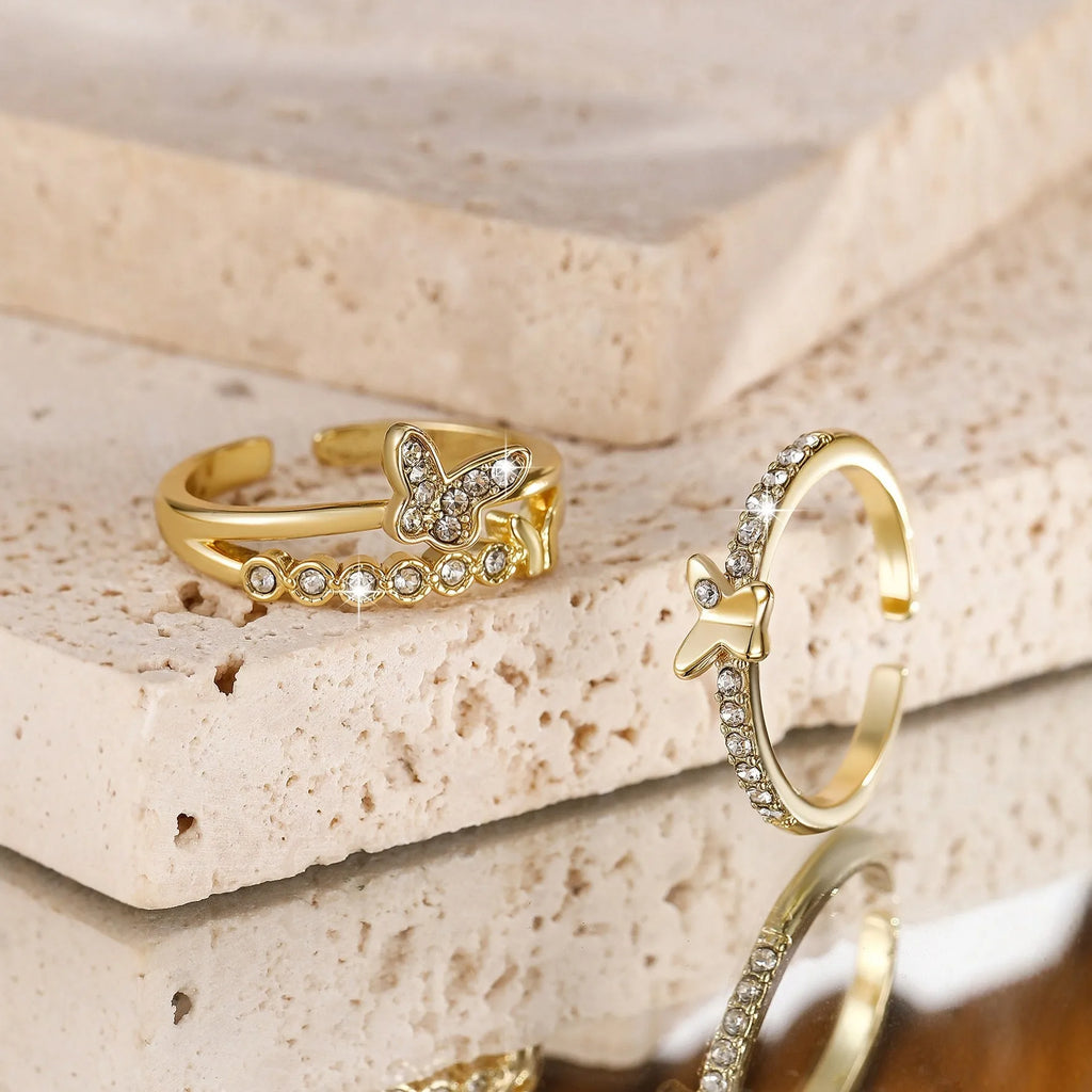 Gold adjustable butterfly ring on finger against white background