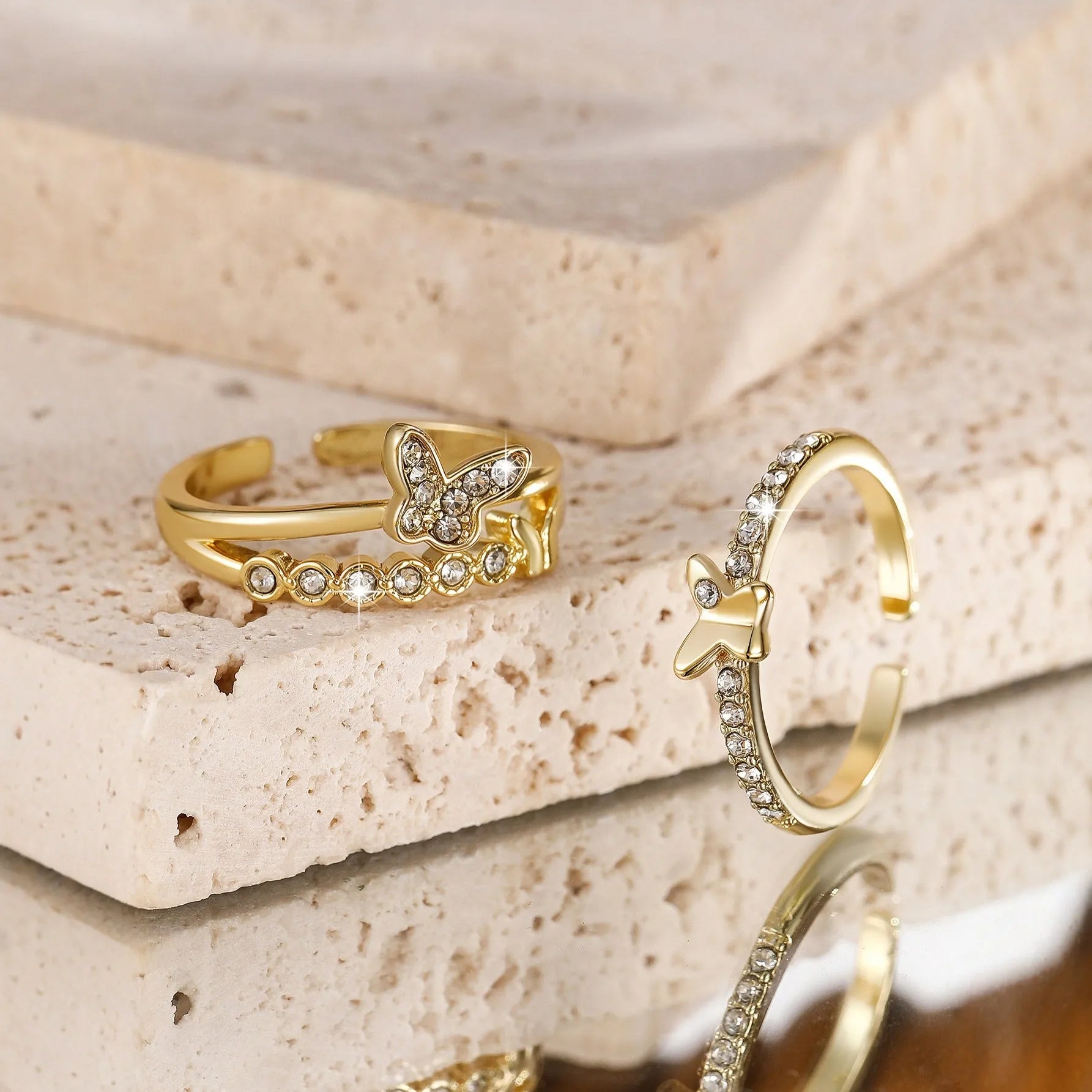 Gold adjustable butterfly ring on finger against white background