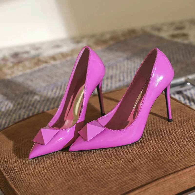 Pink patent leather women's pointed toe stiletto high heels with a buckle detail on the upper.
