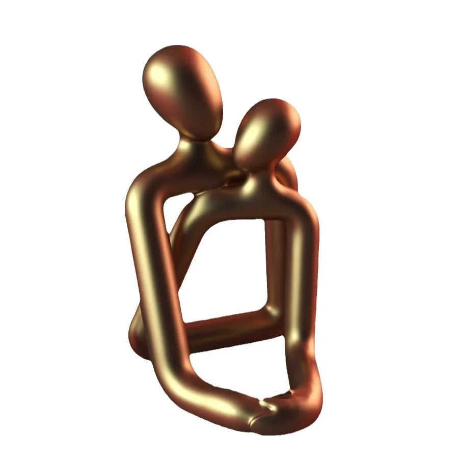 Modern style resin statue of a couple in milky white or gold colour on a wooden surface.