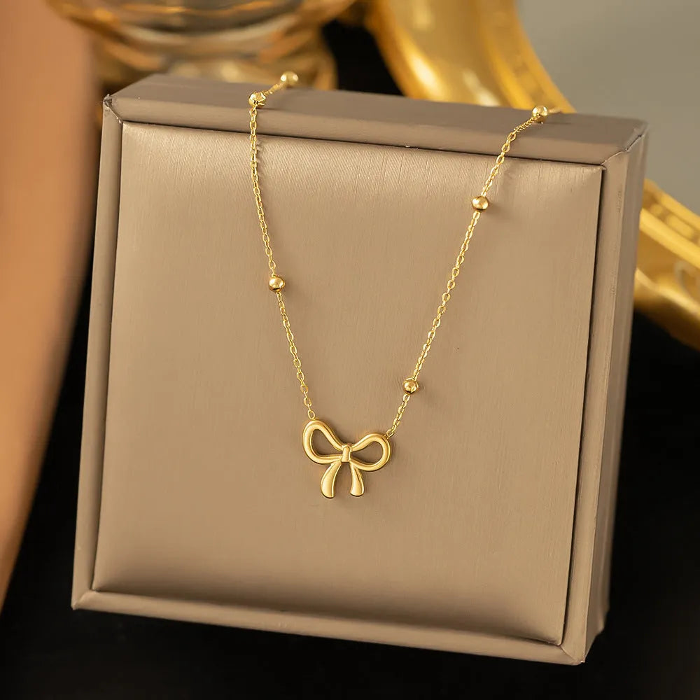 Gold bow necklace with titanium steel cross chain on white background