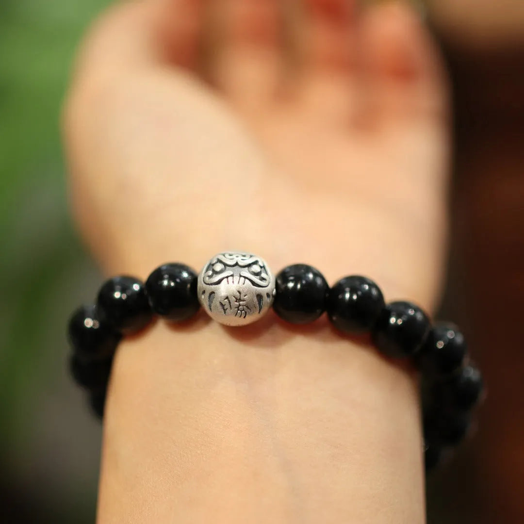 Close-up of a women's bracelet with large 10mm black agate beads and sterling silver details on a wrist.
