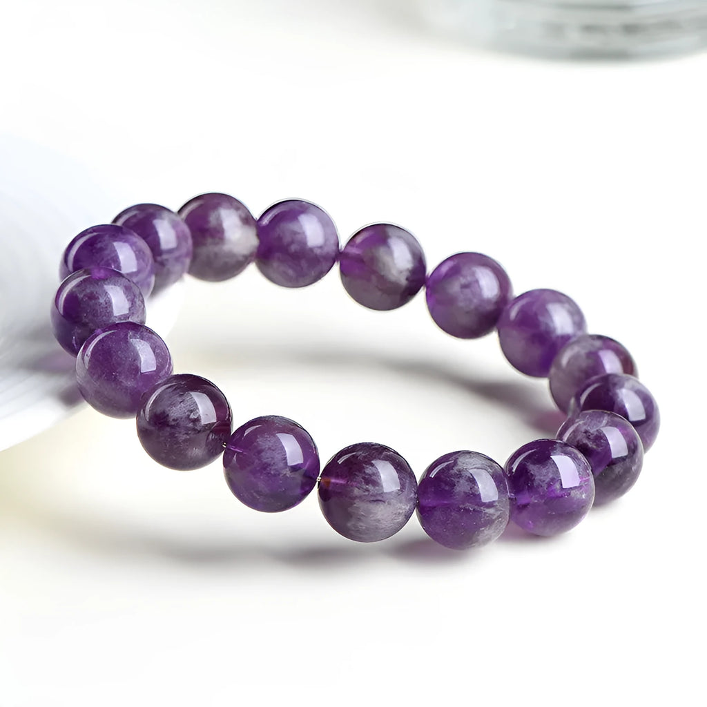 Natural Feather Amethyst crystal bracelet with Ruyi charm beads on a wrist.
