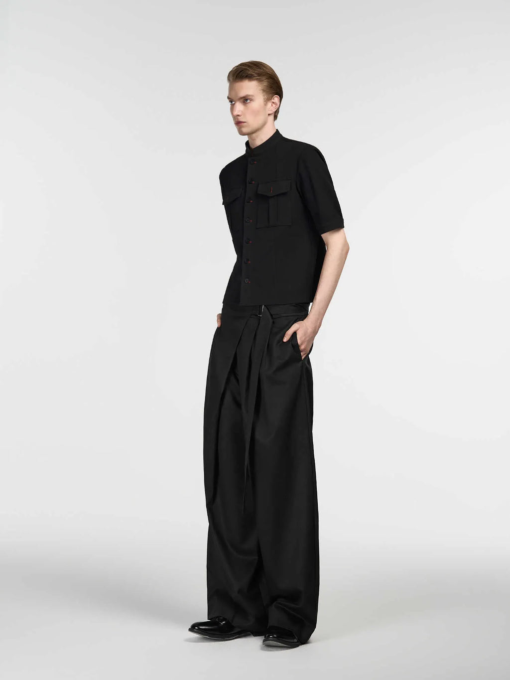 Black straight-leg trousers with a single pleat front and an adjustable waistband, laid flat.