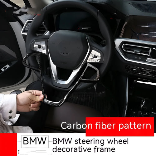 BMW steering wheel button frame decorative trim in black carbon fibre pattern.