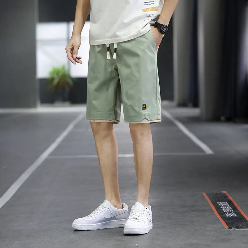 Man modelling loose-fitting straight-leg casual shorts in a solid colour on a beach.