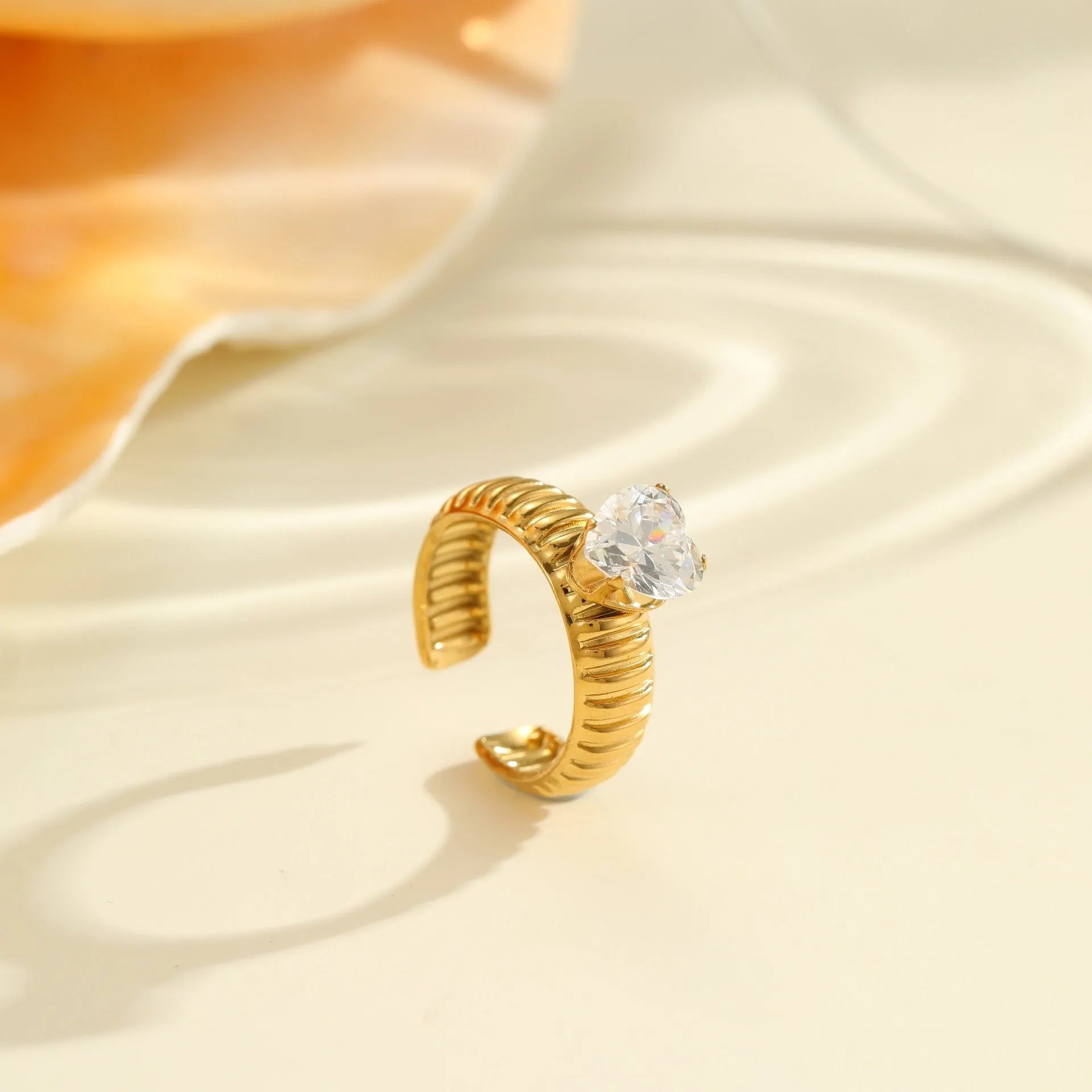 Gold-coloured adjustable stainless steel ring with zircon geometric shapes on white background.