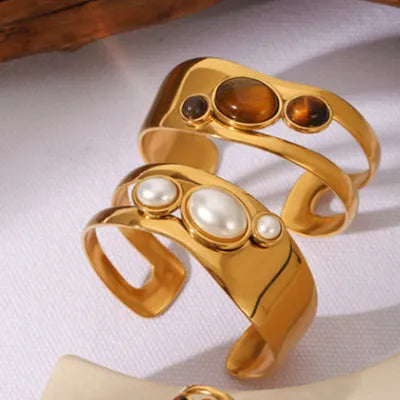 Stainless steel wide face bracelet inlaid with natural tiger eye stone on a neutral background