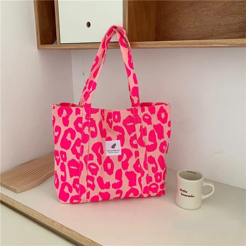 Pink Oxford cloth women's shoulder bag with a large main compartment and a black three-dimensional front pocket.
