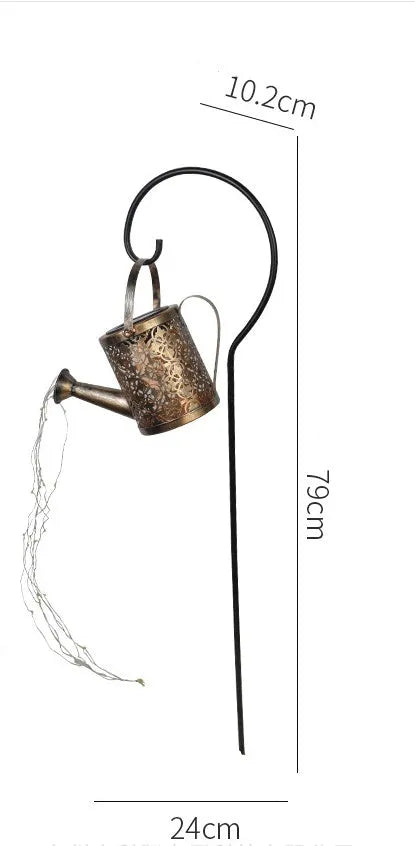 Enchanted watering can solar lamp with warm white star-shaped LED lights in a garden setting