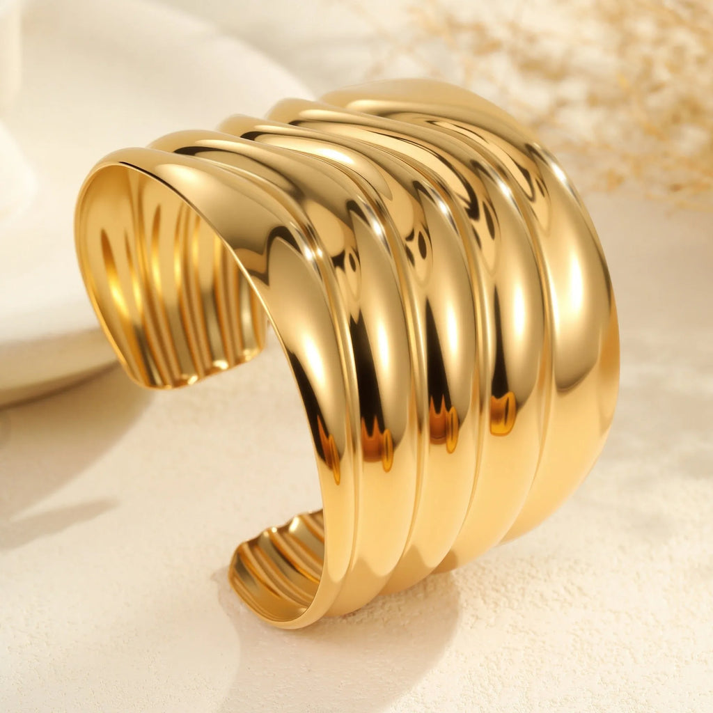 Gold plated wide stainless steel bracelet with a geometric wave shape and a niche opening.