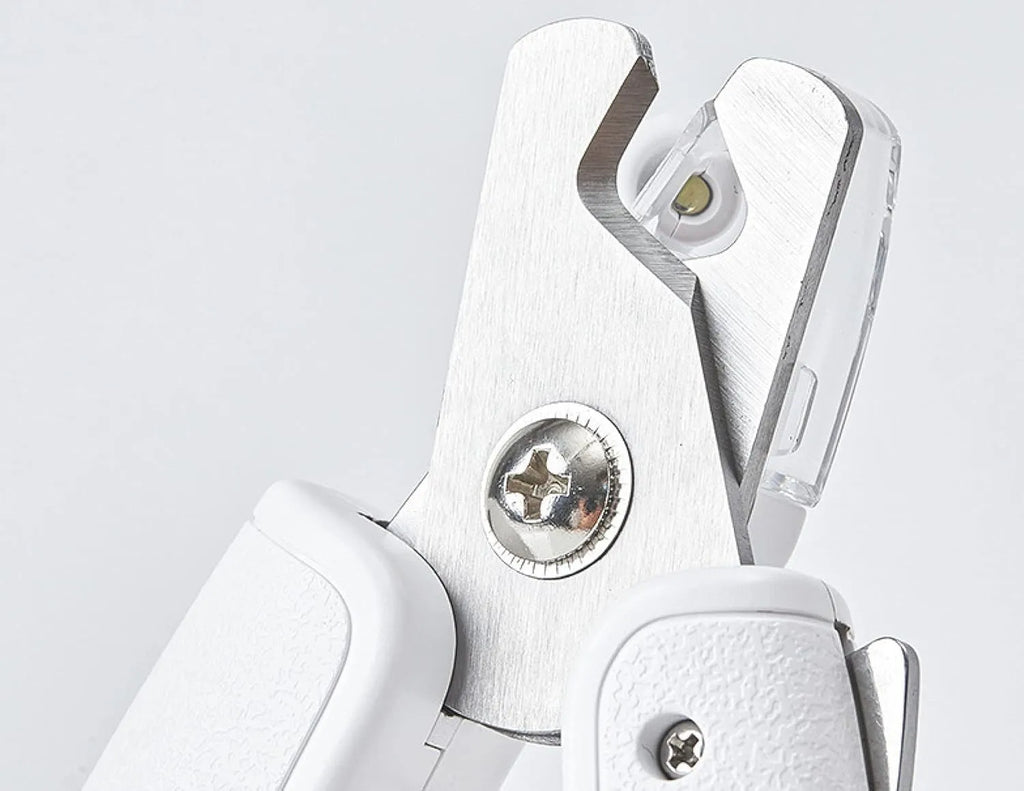 White pet nail clippers with LED light and a transparent anti-splash guard, shown with a nail file.