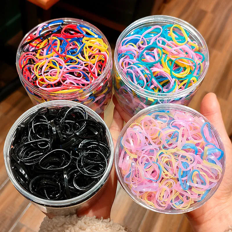 Open reusable container showing hundreds of thin, colourful TPU baby hair ties for toddlers.