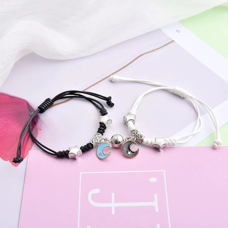 Pair of magnetic suction bracelets with alloy charms in various love and friendship themed designs on a wrist.