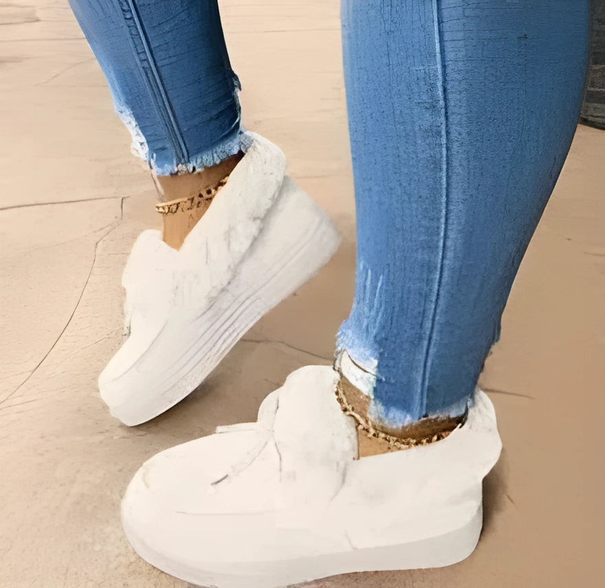 Womens white cotton slip-on shoes with round toe and non-slip rubber sole on a wooden floor.