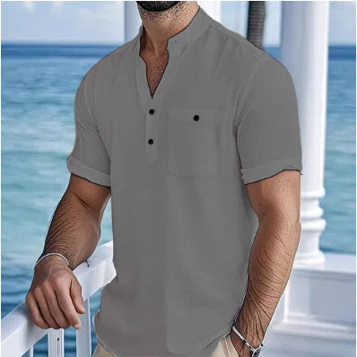 Man wearing a light-coloured, loose fit linen t-shirt with a stand collar and short sleeves.