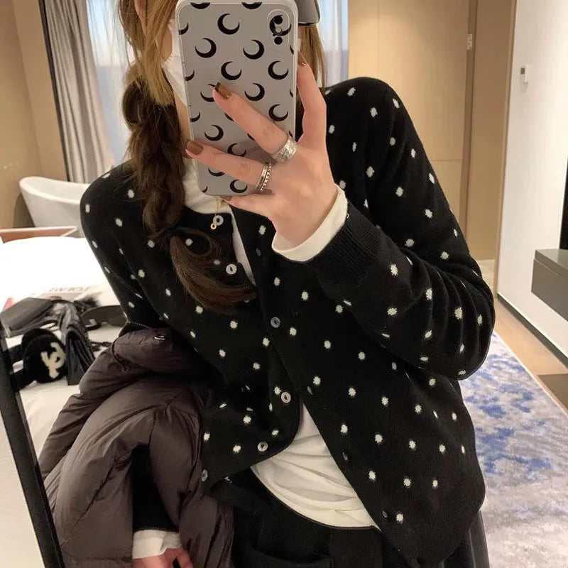 Women's grey dot pattern knitted cardigan with crochet flower details on sleeve.