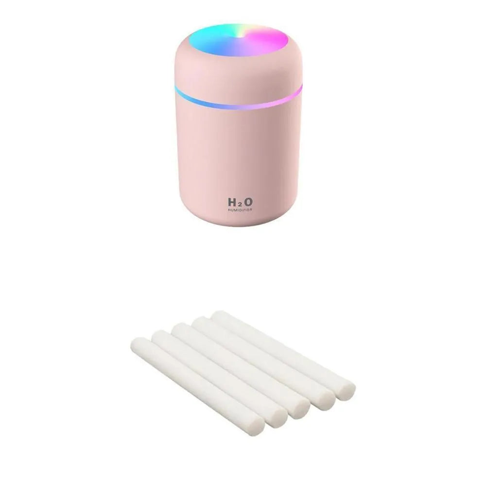 Pink USB desktop humidifier with LED lights and water tank on a wooden desk.