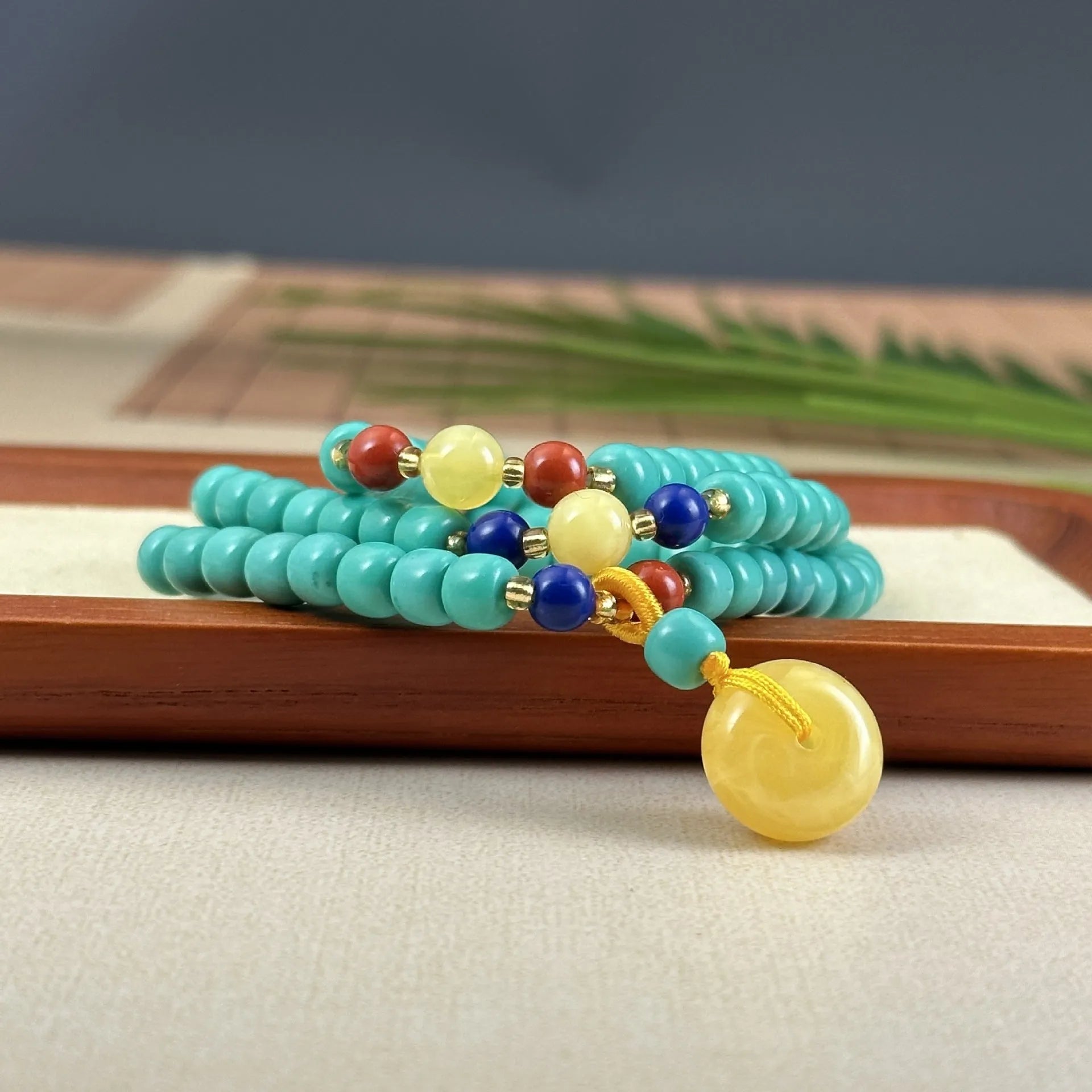 Turquoise lucky pendant necklace with hand-woven mesh flower design on a ball bead chain.