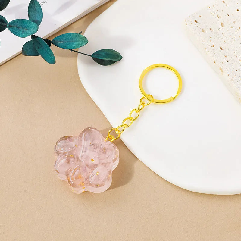 Small natural crystal cat's paw charm on a keyring, showing colour options including pink, red, blue, and purple gemstones.