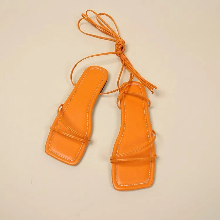 Women's white ankle strap flat sandals with lace-up front and square toe on a rubber sole.