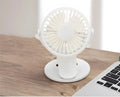 White USB rechargeable mini clip fan attached to a desk edge showing piano button switch and plastic blades.