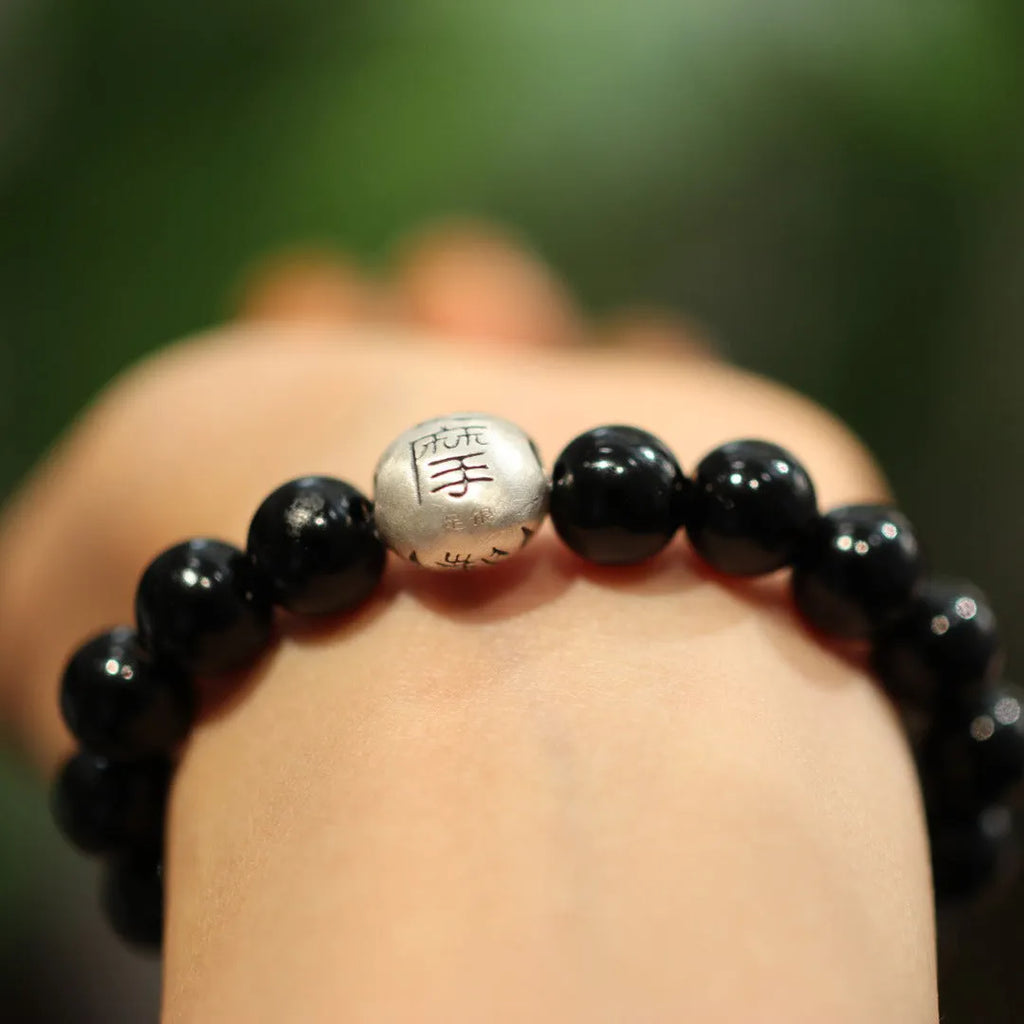 Close-up of a women's bracelet with large 10mm black agate beads and sterling silver details on a wrist.