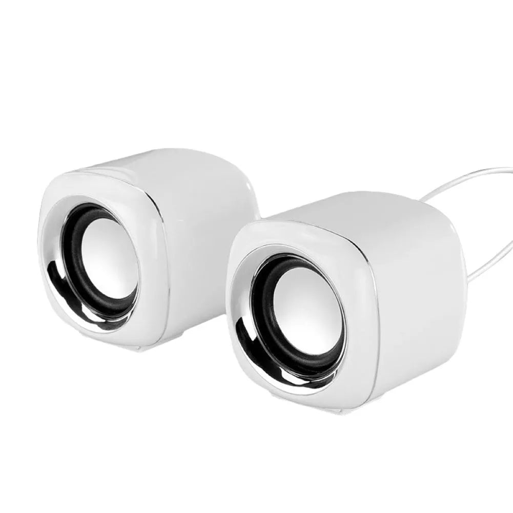 A pair of compact black wired desktop computer speakers with a volume scroll wheel, shown next to a 3.5mm audio plug.