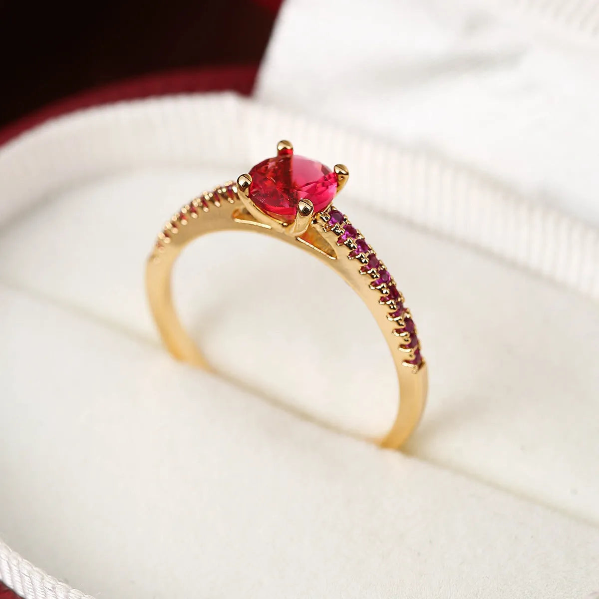Hexagonal geometric copper ring with zircon electroplating in a gold rose red finish on a hand.