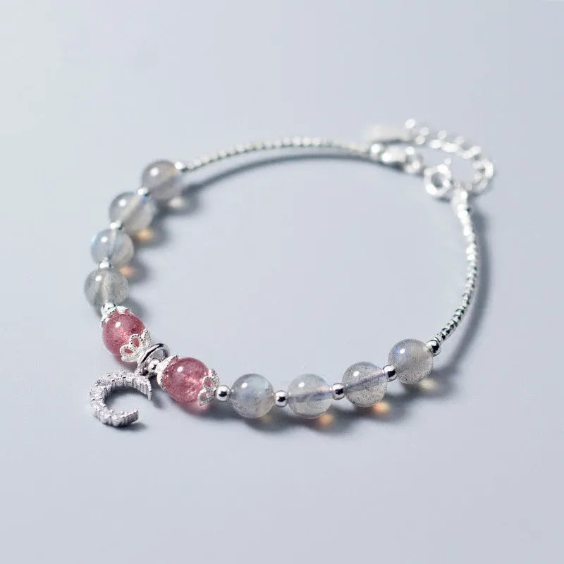 Handmade adjustable moonstone bracelet with crescent moon charm and crystal bead on a white background.