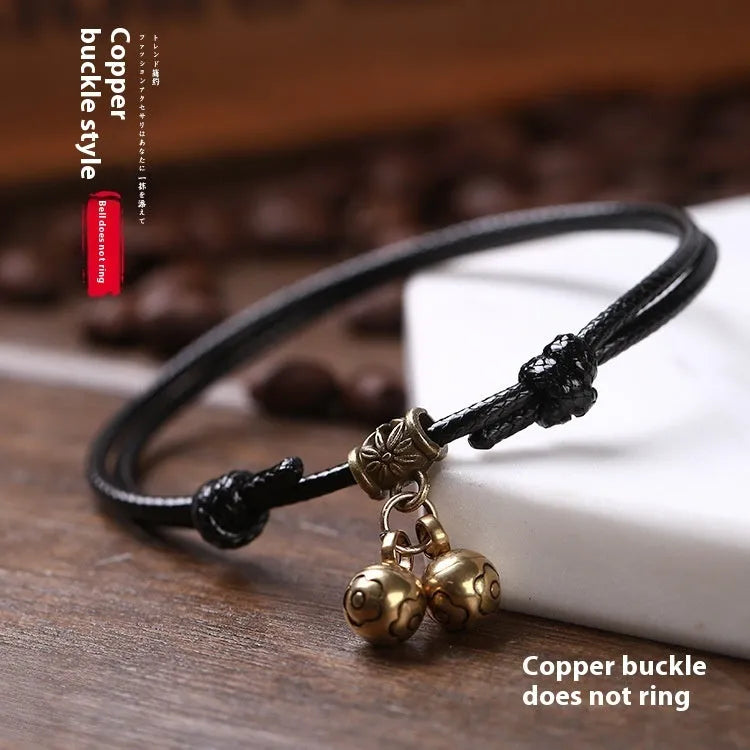 A black nylon rope dog halter collar with a brass bell and adjustable brass buckle on a white background.