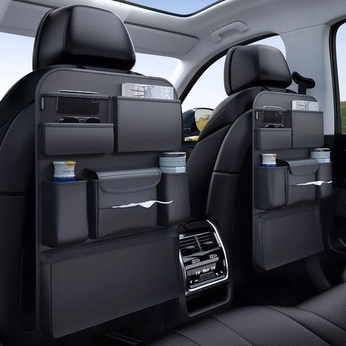 Black leather car seat back hanging storage organiser bag with handle shown mounted on a headrest.
