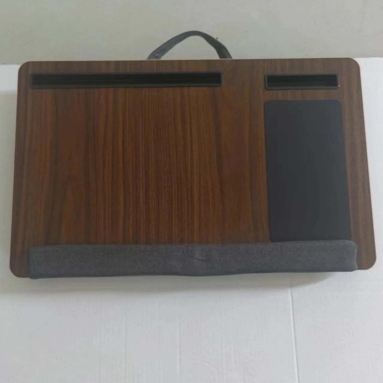 Foldable laptop desk in black walnut colour on a bed with laptop open