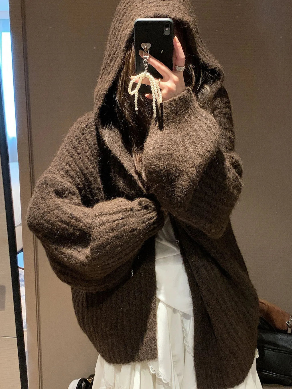Woman wearing a loose-fit, chunky knit hooded cardigan in a macaron colour.