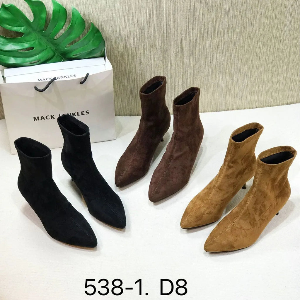 Black pointed toe women's ankle boots with stiletto heels on a neutral background.