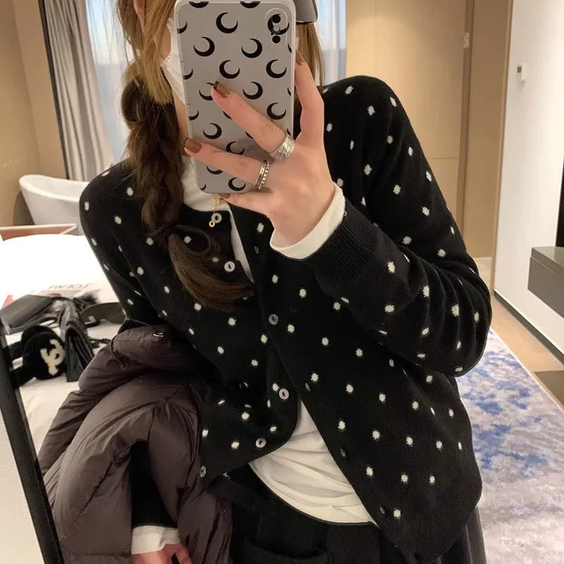 Women's grey dot pattern knitted cardigan with crochet flower details on sleeve.