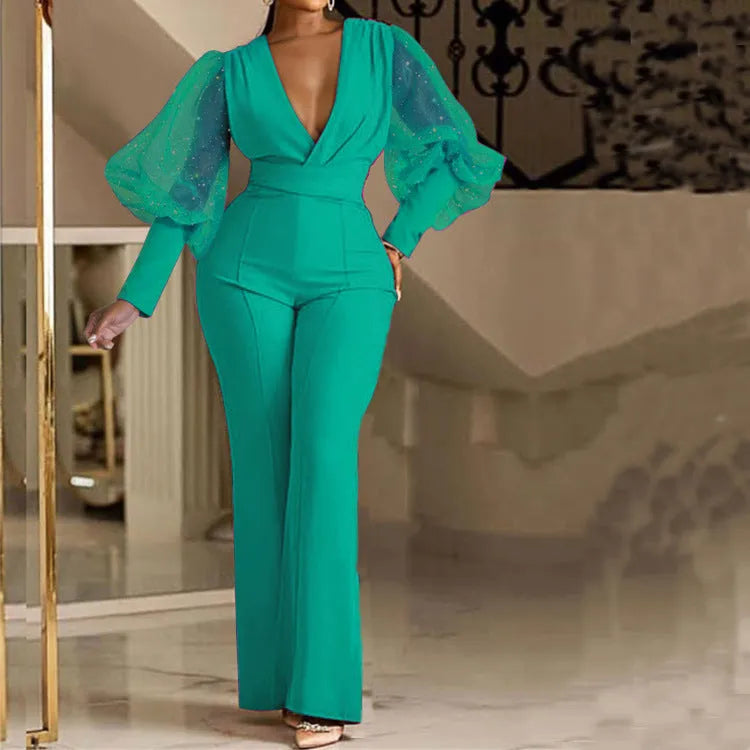 Red women's jumpsuit with mesh stitching on long sleeves, slim fit bodice, wide legs, and elastic waist.