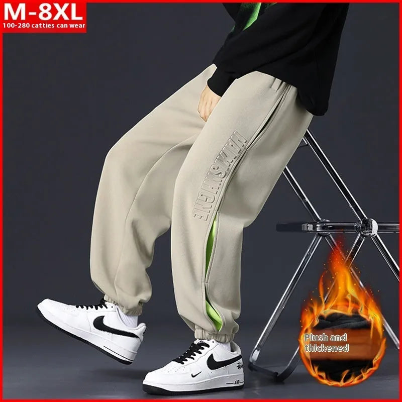 Men's loose black cotton trousers with white collage stitching print and banded ankle cuffs laid flat.