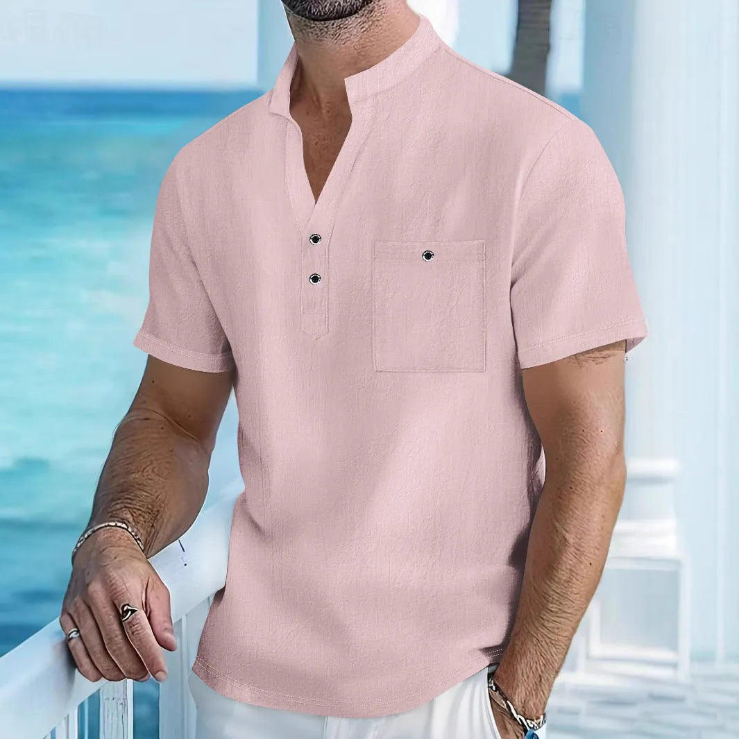 Man wearing a light-coloured, loose fit linen t-shirt with a stand collar and short sleeves.