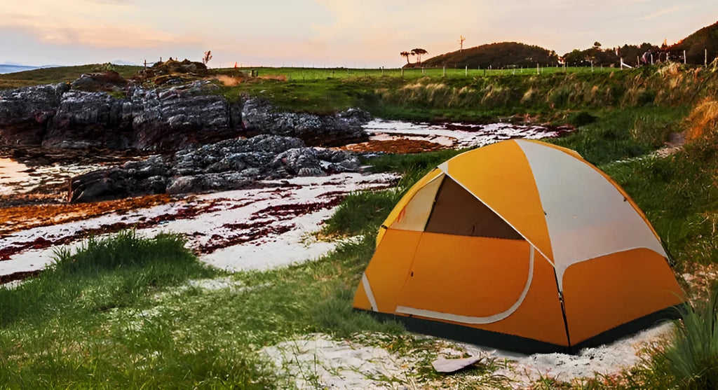 Orange portable 2-person camping tent with fibreglass poles set up outdoors