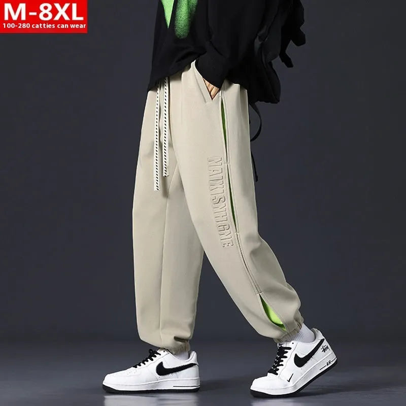 Men's loose black cotton trousers with white collage stitching print and banded ankle cuffs laid flat.