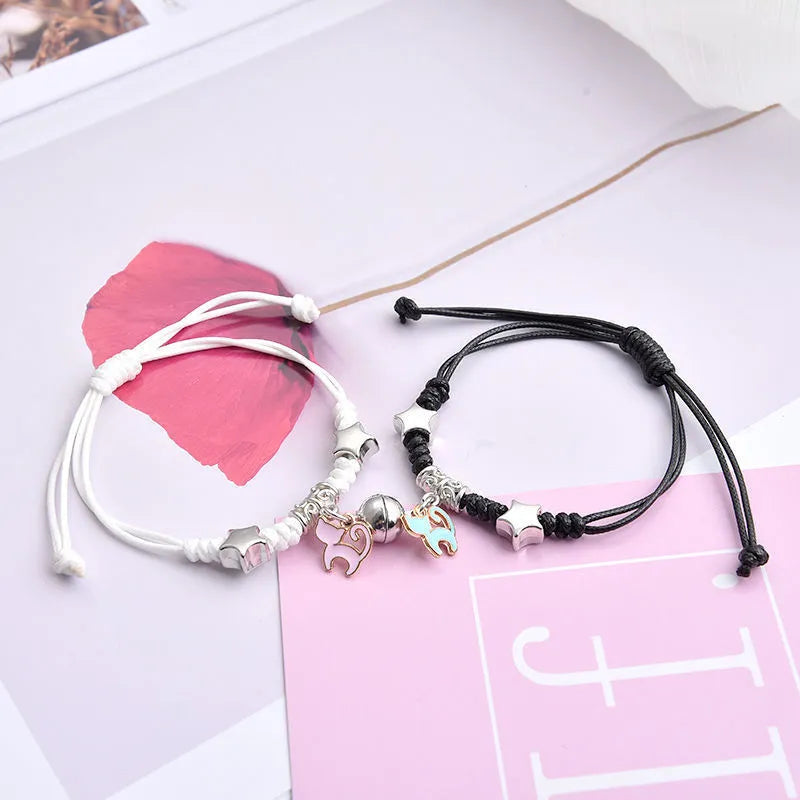 Pair of magnetic suction bracelets with alloy charms in various love and friendship themed designs on a wrist.