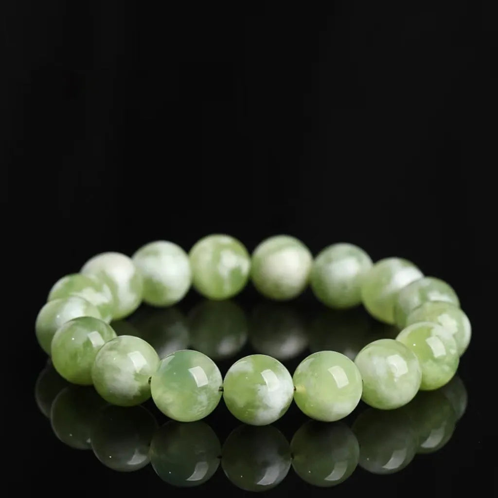 Green milk-in-water Xiuyan jade polished bracelet with geometric beads on a neutral background