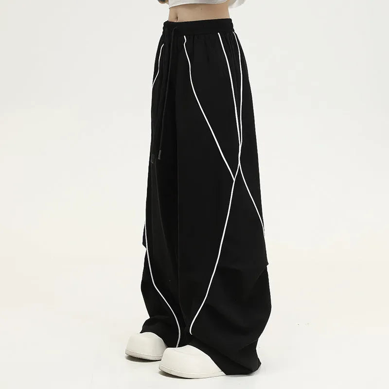 Black pleated wide-leg hip hop sports trousers on a hanger, showing loose fit and striped pattern.