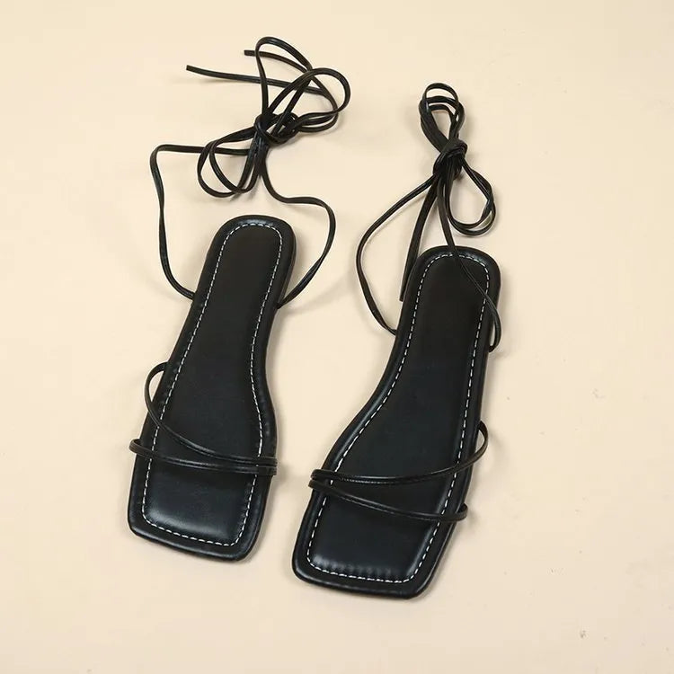 Women's white ankle strap flat sandals with lace-up front and square toe on a rubber sole.